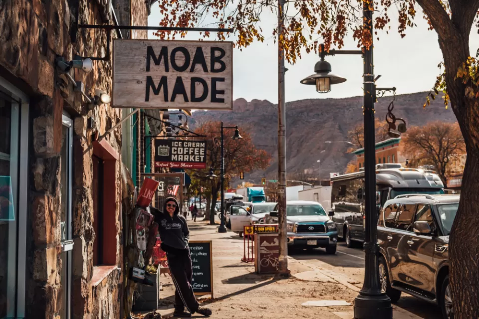 Person standing under sign that says "Moab Made" in downtown Moab, Utah.